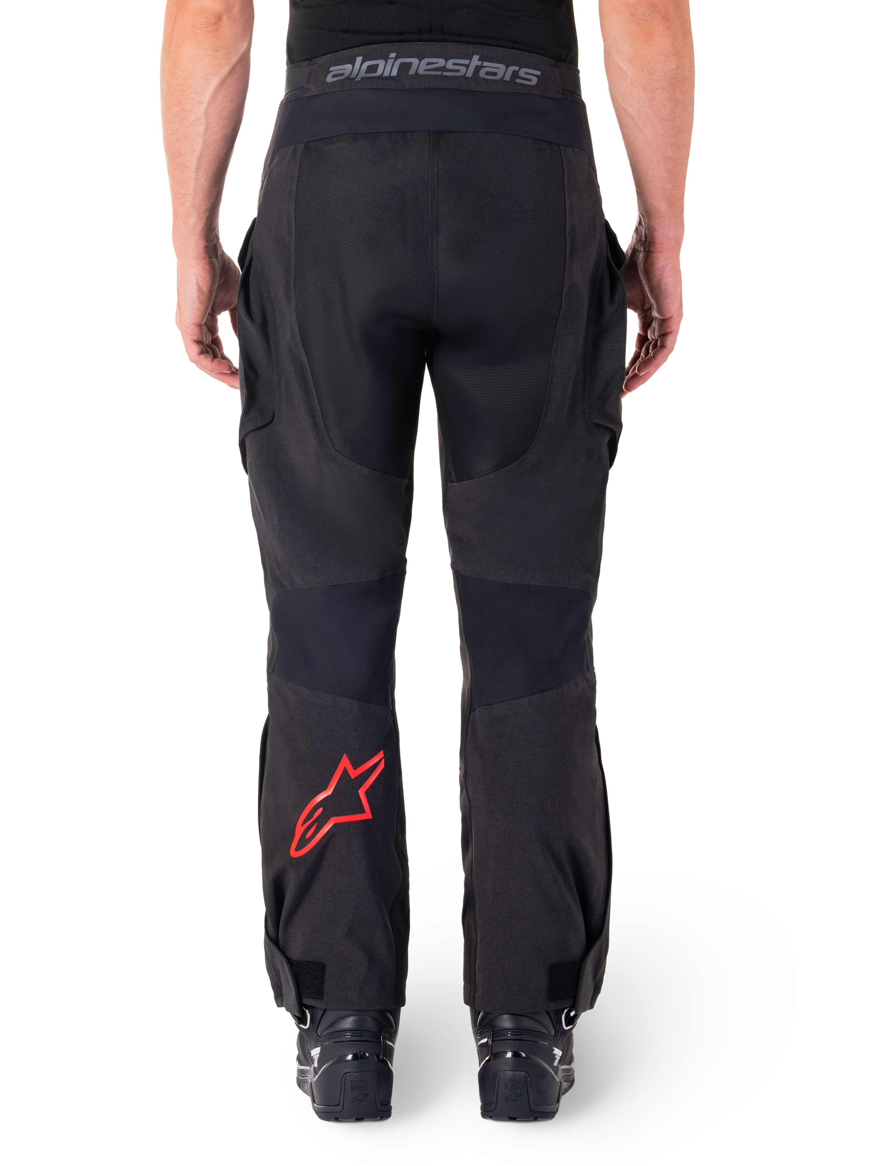 Pantalon Alpinestars Hyde XT Drystar®, pantalon de moto aventure, noir avec logo étoile rouge sur le bas de la jambe, vue arrière, design enduro par-dessus la botte avec empiècements textiles durables et ceinture logotypée.