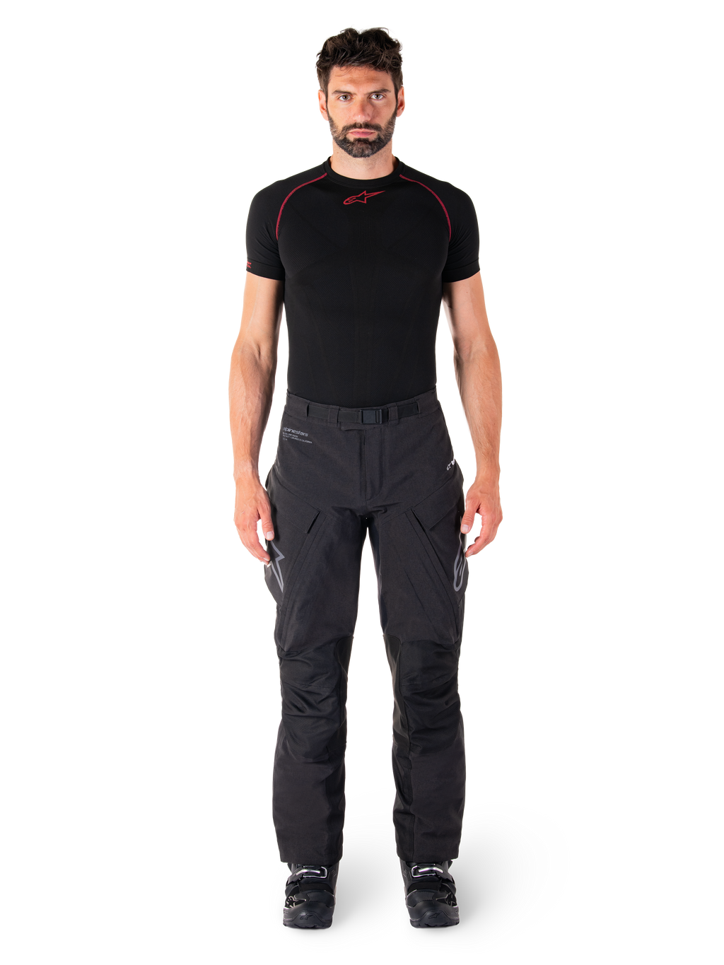 Pantalon Alpinestars Hyde XT Drystar®, pantalon de moto Adventure Touring, noir, porté par un mannequin avec une couche de base noire à manches courtes et des bottes noires, doté d'une matière extensible technique, de panneaux de genoux renforcés et de poches cargo ergonomiques.