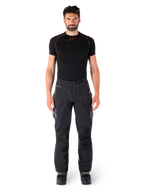 Pantalon Alpinestars Hyde XT Drystar®, pantalon de moto Adventure Touring, noir, porté par un mannequin avec une couche de base noire à manches courtes et des bottes noires, doté d'une matière extensible technique, de panneaux de genoux renforcés et de poches cargo ergonomiques.