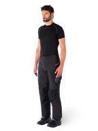 Pantalon Alpinestars Hyde XT Drystar®, pantalon de moto de tourisme d'aventure noir porté par un mannequin avec un maillot de compression noir et des bottes noires, doté d'une construction technique imperméable et du logo Drystar®XF