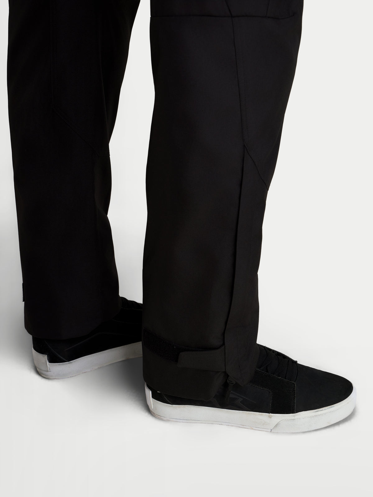 Alpinestars C-1 Waterproof Pantalons, pantalon de moto urbain contemporain pour homme noir, vue rapprochée montrant la construction droite de la jambe inférieure et les ouvertures de jambes étendues portées avec des chaussures de moto