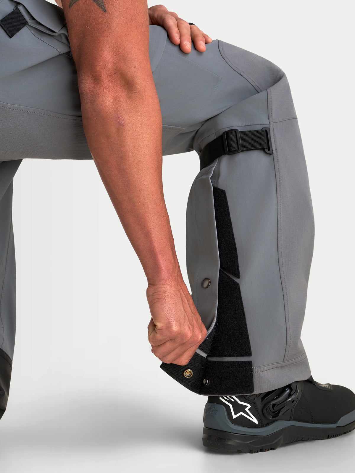 Alpinestars Maxdura Drystar XF Laminated Pantalons, pantalon de moto adventure gris et noir pour homme, mettant en valeur la construction ajustable du bas de jambe et la coupe sur-la-botte avec des bottes de moto noires