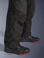Alpinestars Andes V4 Drystar® Pants - Court, noir, gros plan sur le détail du bas de la jambe montrant la construction textile, fermeture éclair verticale pour la ventilation et chevilles ajustables, porté avec des bottes de moto noires