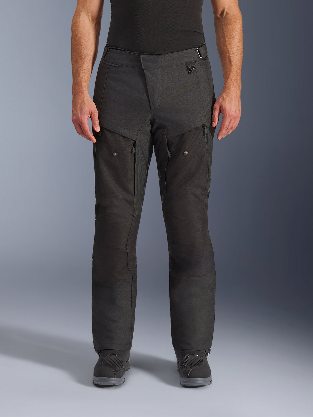 Pantalon Alpinestars Cusco Drystar®, pantalon de moto adventure, noir, vue de face, doté de ventilations zippées sur les cuisses et d'une taille ajustable, construction en textile ripstop et 600D durable, porté avec des bottes noires