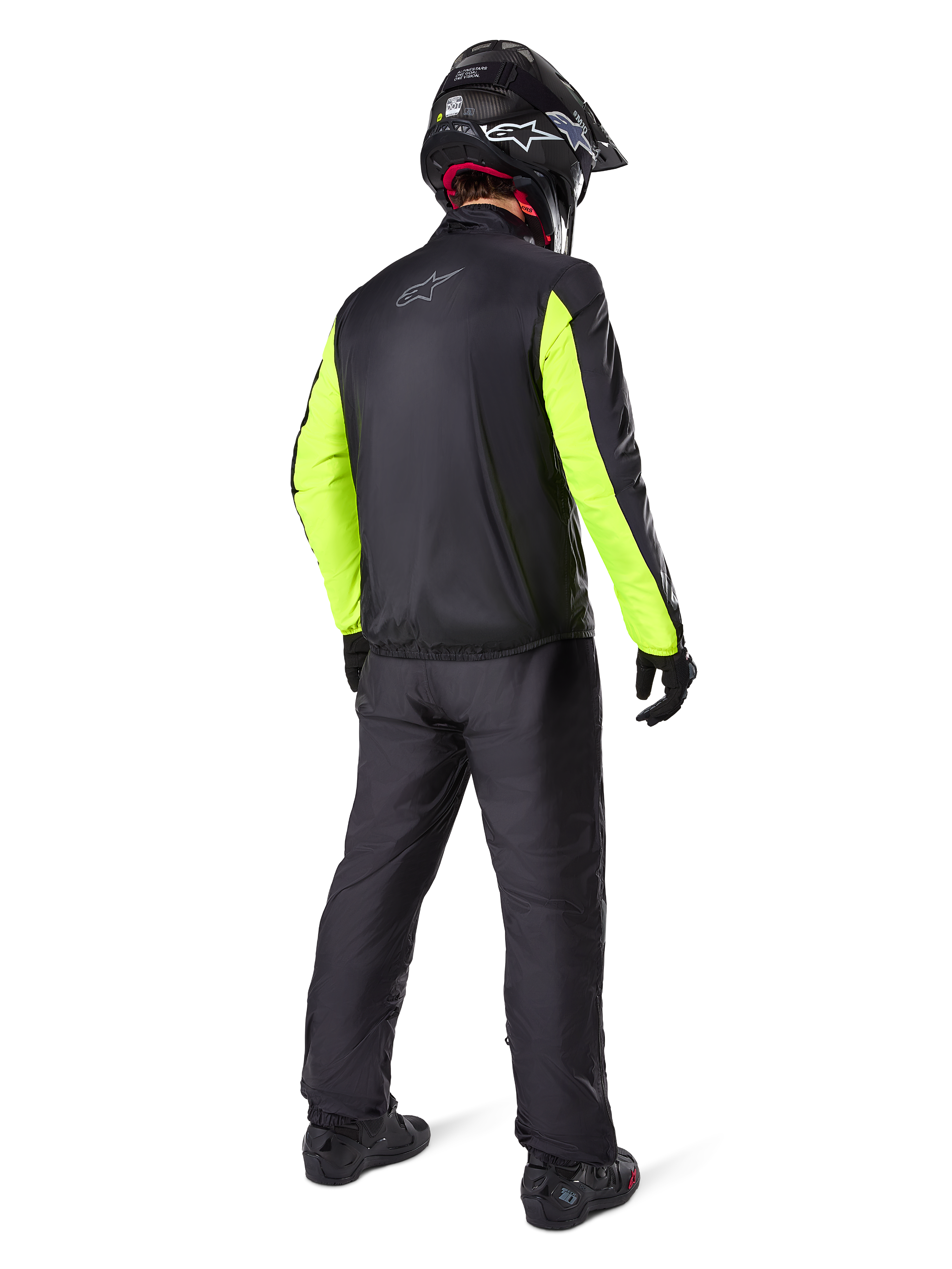 Rider from the rear wearing Alpinestars Bogotá Pro Drystar® 3 Seasons Pants in Black, paired with a black jacket featuring fluorescent yellow sleeves, black adventure helmet, and boots, complete adventure touring gear
