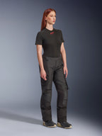 Alpinestars Stella Andes V4 Drystar®, pantalon de moto pour femme, noir, porté avec un t-shirt noir à manches courtes avec logo rouge et des chaussures techniques, design adventure touring avec panneaux renforcés et zips de ventilation, vue de trois-quarts en pied