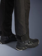 Pantalon Alpinestars Stella Andes V4 Drystar®, noir, vue rapprochée du bas de la jambe et de la cheville, avec fermeture éclair latérale et sangle de cheville réglable auto-agrippante, porté avec des bottes de moto Alpinestars noires