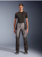 Alpinestars Stella Andes V4 Drystar Pants, pantalon de moto adventure touring pour femme, noir et gris foncé, porté par un mannequin femme avec une couche de base noire et des bottes de moto, doté de panneaux textiles renforcés et de poches cargo pour la conduite aventure