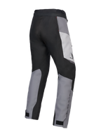 Pantalon Alpinestars 2025 Honda Stella ST-1 Waterproof pour femme, pantalon de touring moto, gris glace, gris foncé et noir, vue de trois-quarts arrière montrant la construction textile durable, les empiècements contrastés gris et noirs, le logo Honda sur la hanche et les pattes de serrage aux chevilles.