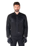 Alpinestars Mootant Waterproof Parka, Black motorcycle jacket, Front view on male model, featuring modular textile construction with mesh panels for ventilation, ribbed collar, and zippered pockets, worn with black gloves with white Alpinestars branding