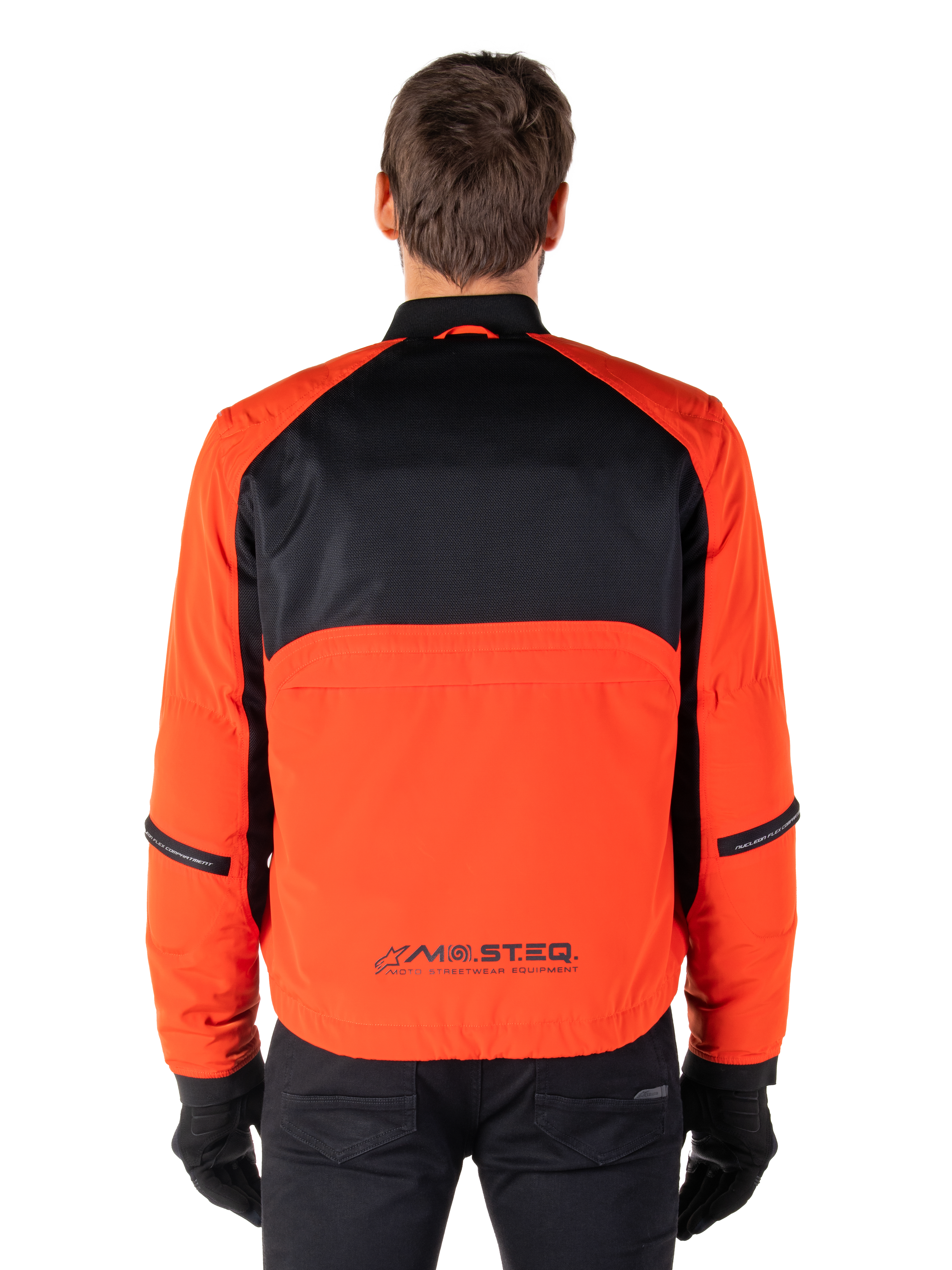 Alpinestars Mootant Waterproof Parka, Motorcycle Jacket, Spicy Orange and Black, Rear View, featuring black mesh upper back and orange lower panel with MO.ST.EQ. logo, worn with black pants and gloves