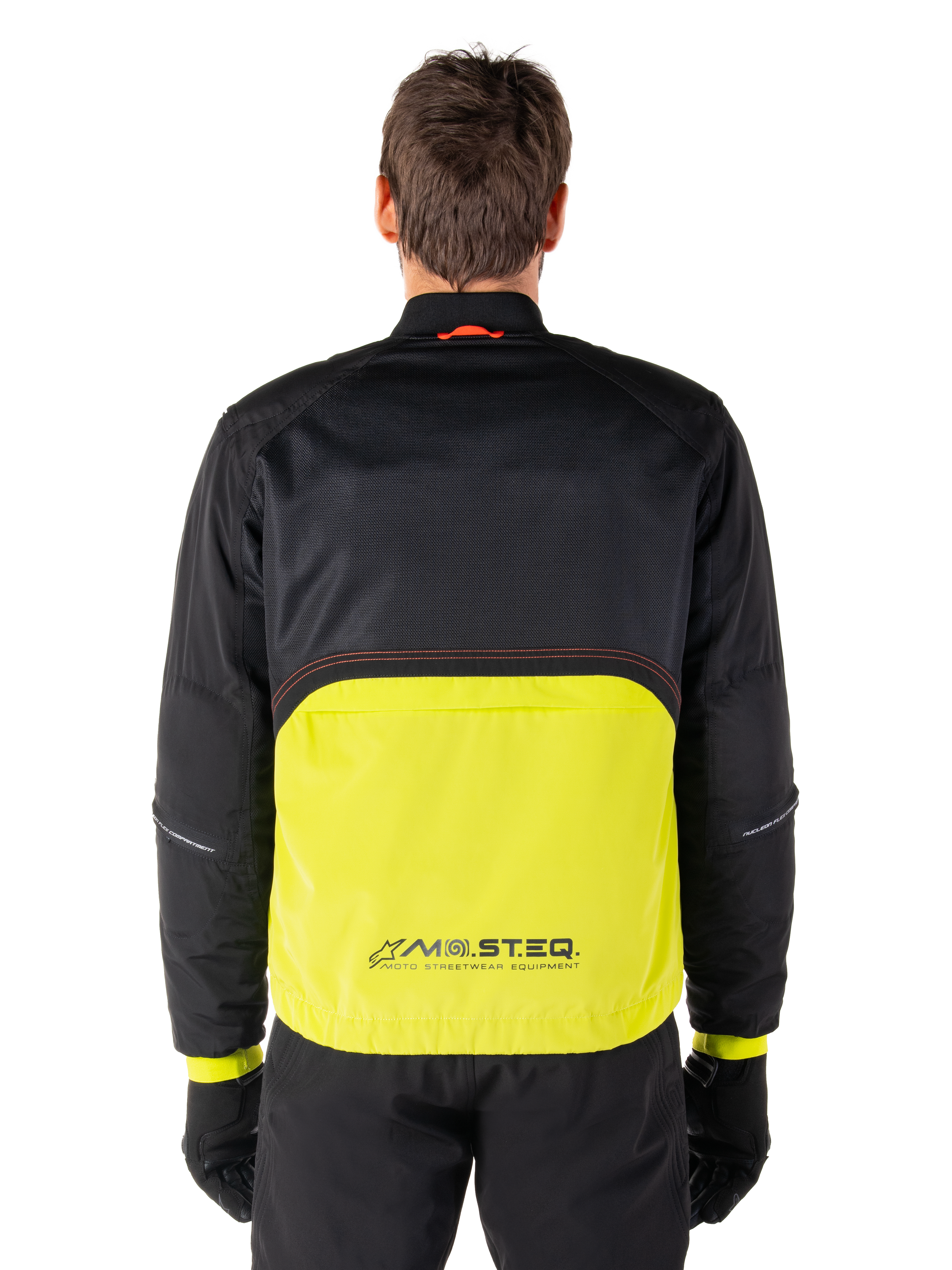 Parka imperméable Alpinestars Mootant, veste de moto, Lime Punch et noir, vue de dos présentant une partie supérieure en mesh noir pour la ventilation et une partie inférieure lime avec le logo MO.ST.EQ., portée avec un pantalon et des gants noirs