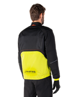 Parka imperméable Alpinestars Mootant, veste de moto, lime punch et noir, vue arrière montrant la partie supérieure en maille noire et la partie inférieure en vert lime éclatant, avec marquage MO.ST.EQ., portée avec un pantalon de moto et des gants noirs
