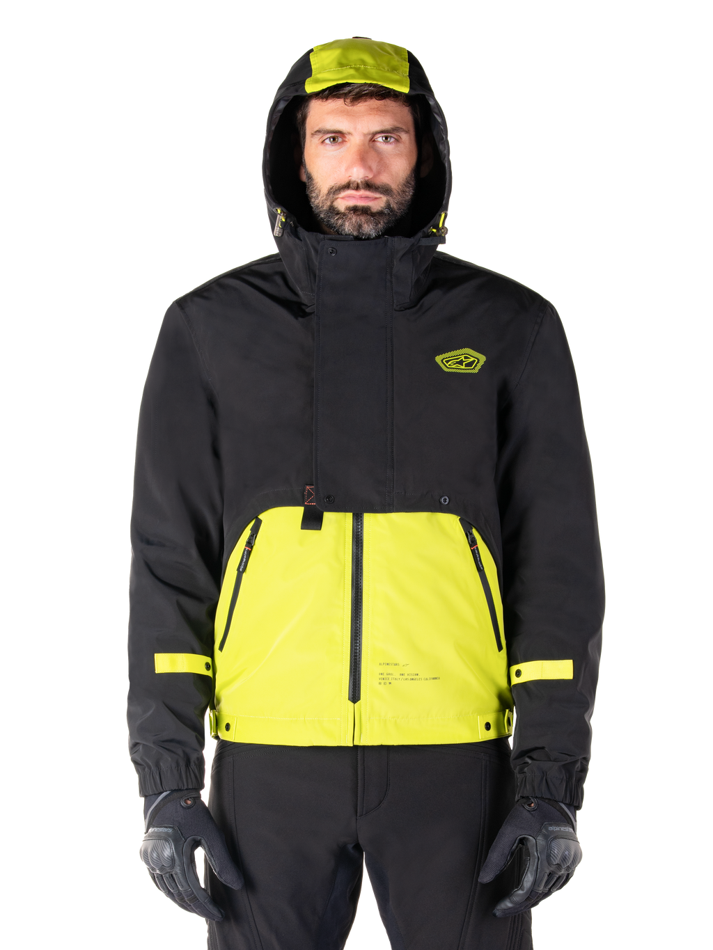 Parka imperméable Alpinestars Mootant, veste de moto Lime Punch Black, vue de face, conception modulaire 3-en-1 avec partie supérieure noire et section inférieure vert citron éclatant, dotée d'une capuche à cordon de serrage et d'un logo sur la poitrine, portée avec un pantalon noir et des gants de moto