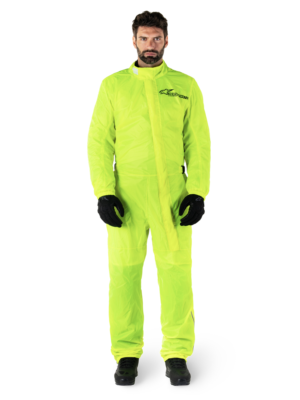 Alpinestars Hurricane Rain V2 Suit, combinaison de pluie pour moto, jaune fluo, modèle masculin portant une protection intégrale avec gants et bottes noirs, col montant avec rabat-tempête sur le devant, logo réfléchissant sur la poitrine, équipement imperméable haute visibilité