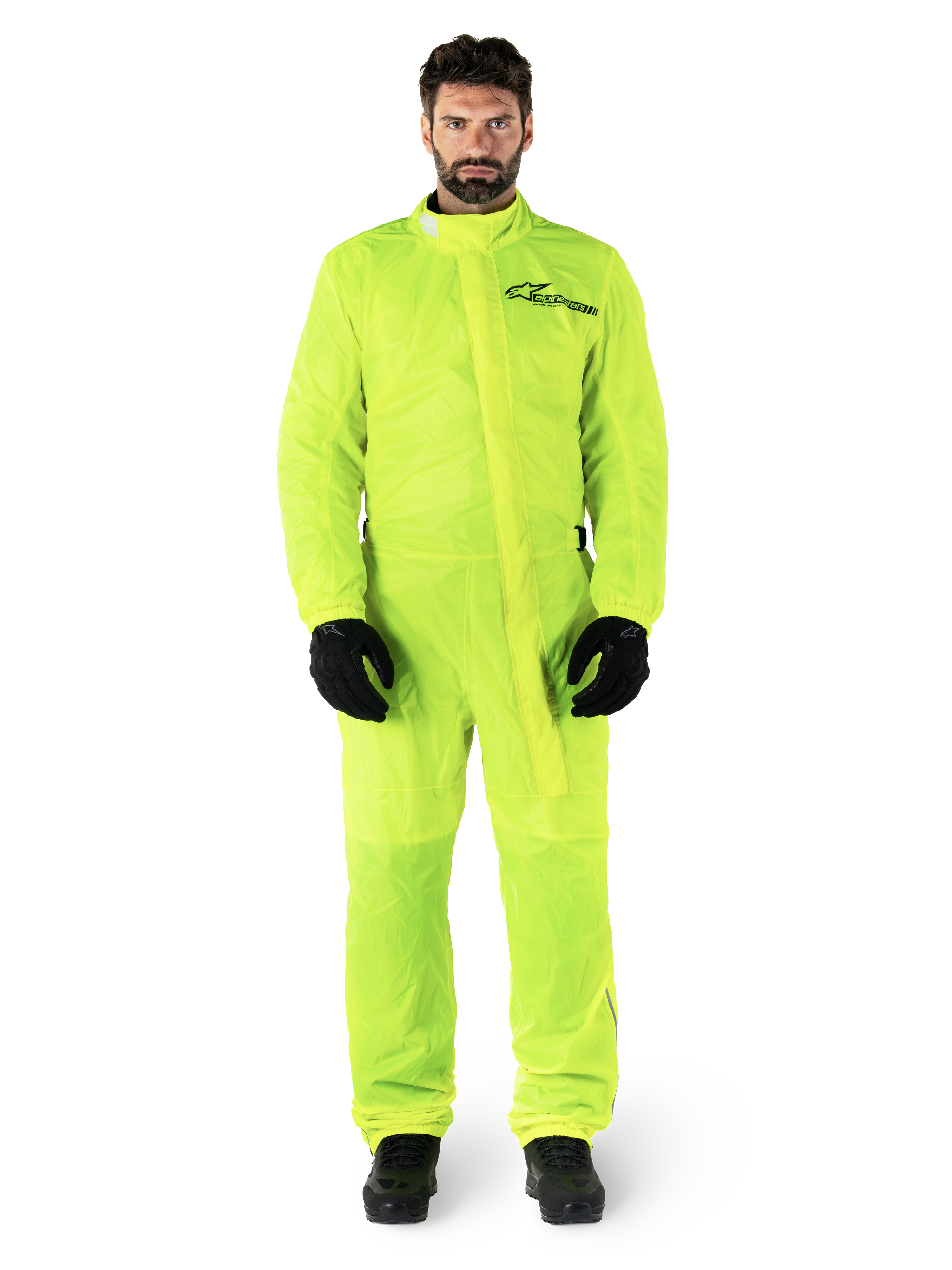 Alpinestars Hurricane Rain V2 Suit, combinaison de pluie pour moto, jaune fluo, modèle masculin portant une protection intégrale avec gants et bottes noirs, col montant avec rabat-tempête sur le devant, logo réfléchissant sur la poitrine, équipement imperméable haute visibilité