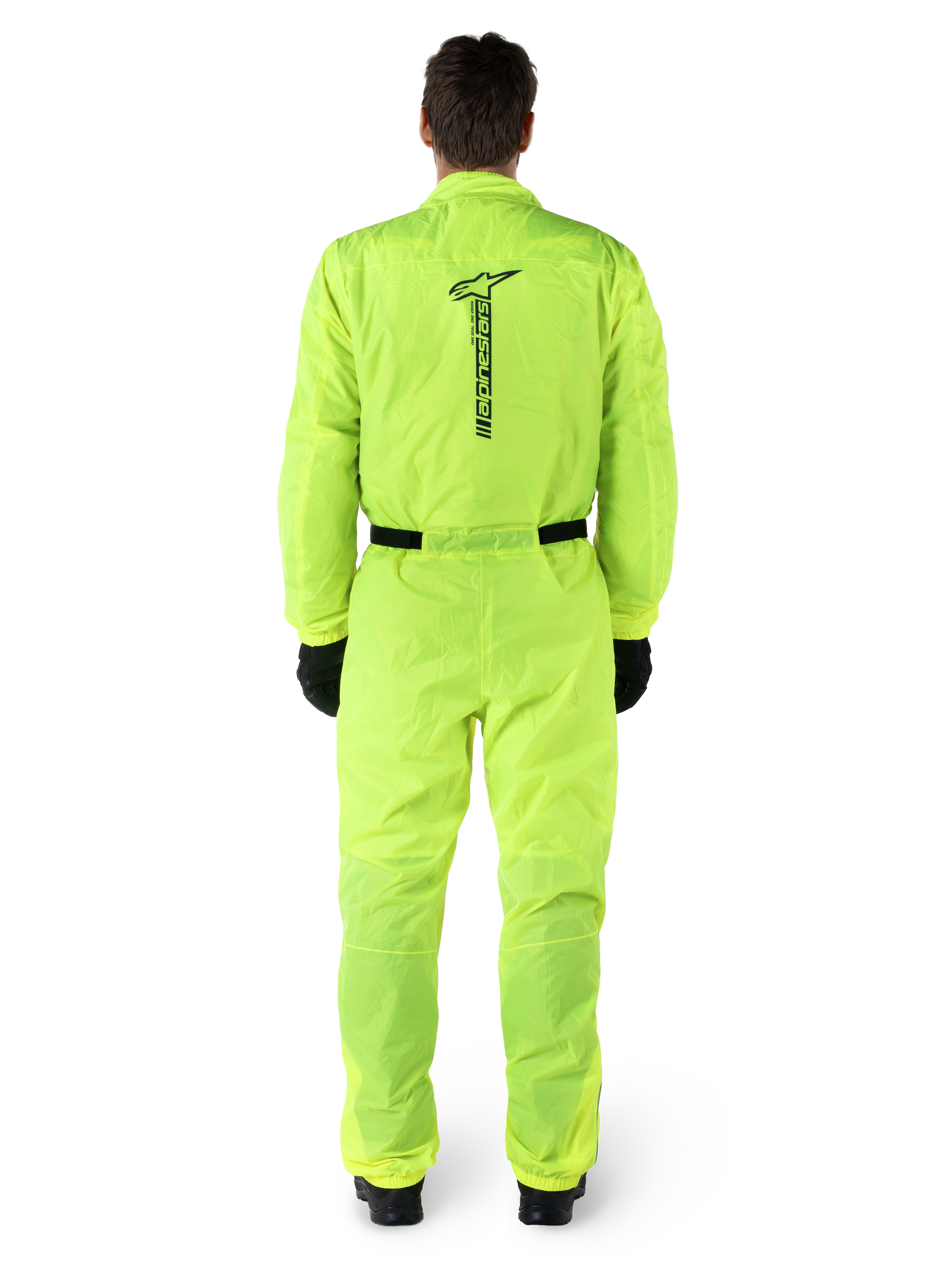 Alpinestars Hurricane Rain V2 Suit, combinaison de pluie de moto une pièce, jaune fluo, vue arrière avec marquage Alpinestars noir vertical, taille et poignets élastiqués, portée avec des gants et des bottes noirs, équipement de conduite imperméable et coupe-vent