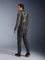 Veste Alpinestars Axton, veste de moto pour homme, noir et anthracite, vue arrière présentant un grand logo gris enveloppant et des panneaux accordéon aux épaules, portée avec un pantalon de moto sombre et des baskets noires, style urbain contemporain avec un héritage de course.
