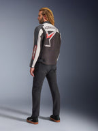 Veste Alpinestars Axton, veste de moto, noir, blanc cassé et rouge vif, vue arrière portée par un mannequin homme, arborant un grand logo étoile et le nom de la marque Alpinestars dans le dos, design d'inspiration vintage racing avec des panneaux en accordéon, associée à un pantalon noir et des baskets