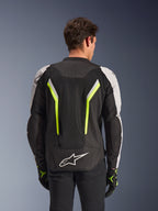 Veste Alpinestars AST V3 Air, Noir Argent Jaune Fluo, vue arrière sur modèle, veste de moto en textile dotée de panneaux de ventilation en maille double technologie, bandes verticales jaune fluo, manches argentées et logo Alpinestars blanc sur le bas du dos.