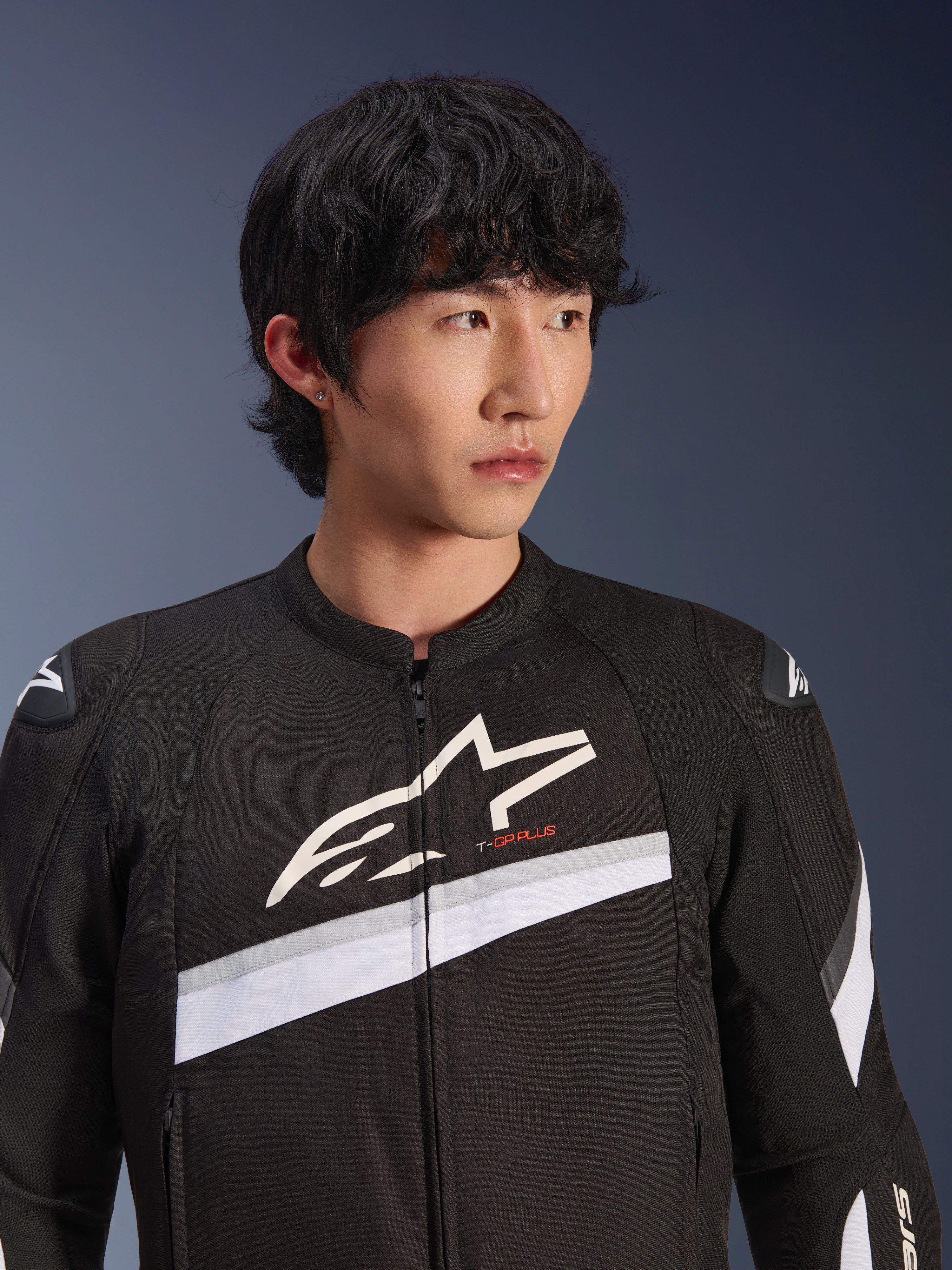 Veste Alpinestars T-GP Plus R V4, noir et blanc, veste de moto en textile portée par un mannequin homme, avec un grand logo étoile blanc sur la poitrine, des bandes diagonales blanches et des protections d'épaules DFS Lite, équipement de route d'inspiration sportive.