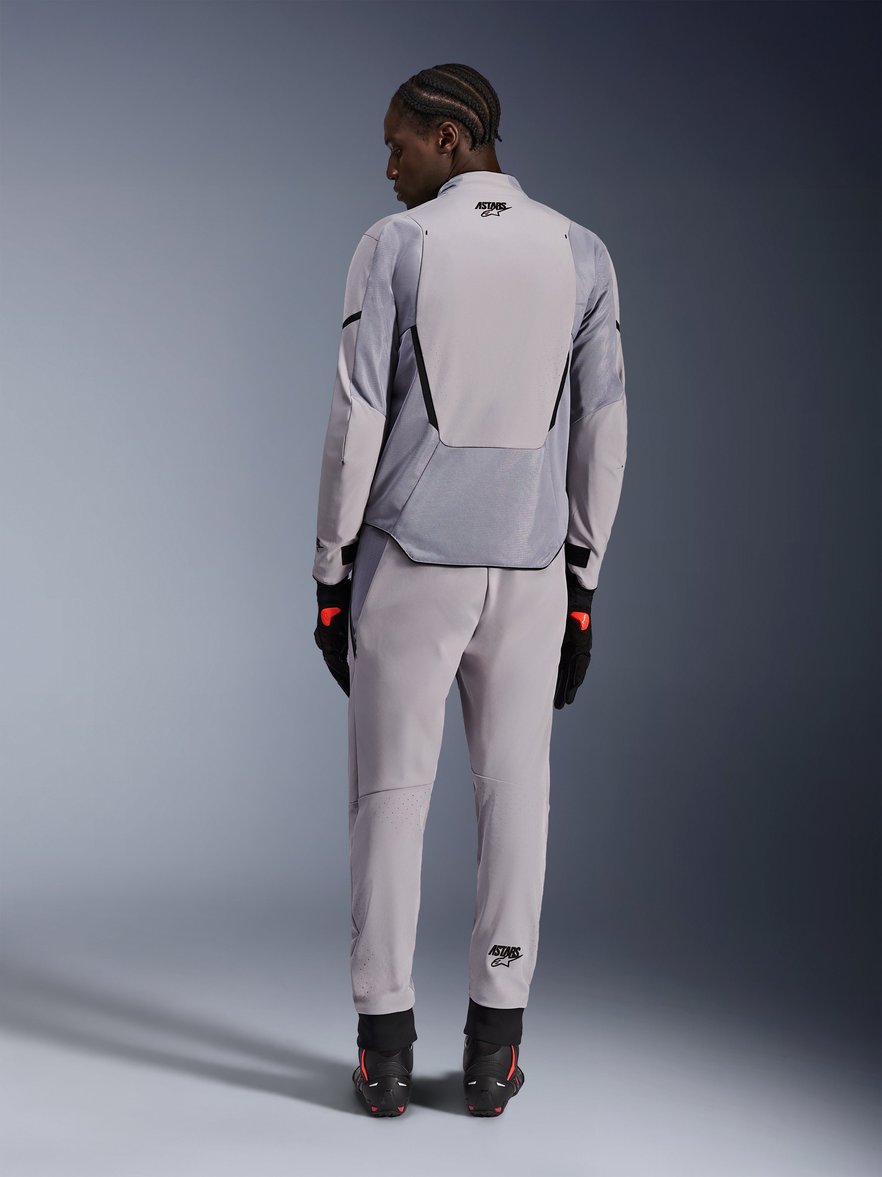 Veste Alpinestars Aeroshell Airflow, Gris moyen anthracite, vue de dos sur un mannequin, dotée de panneaux en maille technique et de zones de ventilation perforées au laser, portée avec un pantalon gris assorti et un équipement de moto noir, design à coupe sportive pour haute performance.