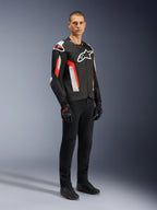 Veste Alpinestars T-GP Air, Noir Rouge Fluo, portée par un mannequin avec un pantalon de moto et des gants noirs, dotée de panneaux textiles perforés au laser, logos Alpinestars blancs et accents rouges, veste de moto sportive pour la conduite sur route par temps chaud