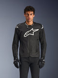 Veste Alpinestars T-GP Air, veste de moto en textile noir avec un grand logo étoile blanc sur la poitrine, dotée de panneaux de ventilation perforés et de mesh 3D, sliders d'épaules externes, portée avec des gants noirs et blancs, design sportif élégant pour la conduite sur route par temps chaud