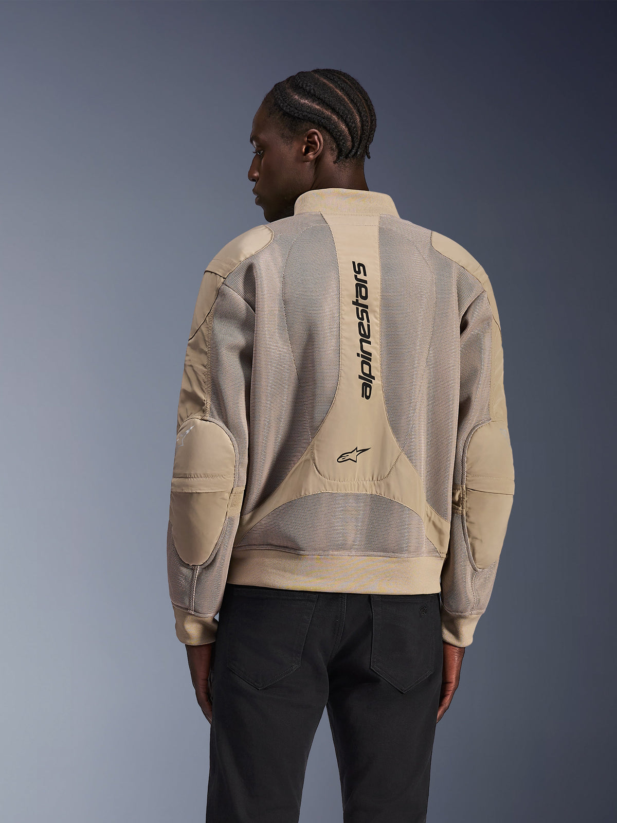 Veste Alpinestars Flight Air, veste de moto urbaine, tan, vue arrière présentant des panneaux en maille 3D étendus et un marquage Alpinestars vertical au dos, design inspiré du bomber avec ourlet côtelé, portée par un mannequin avec un pantalon noir