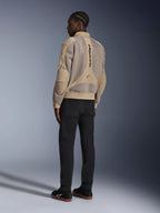Veste Alpinestars Flight Air, veste de moto urbaine en textile, marron, vue arrière montrant de larges panneaux en maille 3D et un logo vertical, silhouette de style bomber avec col et ourlet côtelés, associée à un pantalon noir et des chaussures noires pour un style de conduite d'inspiration urbaine.