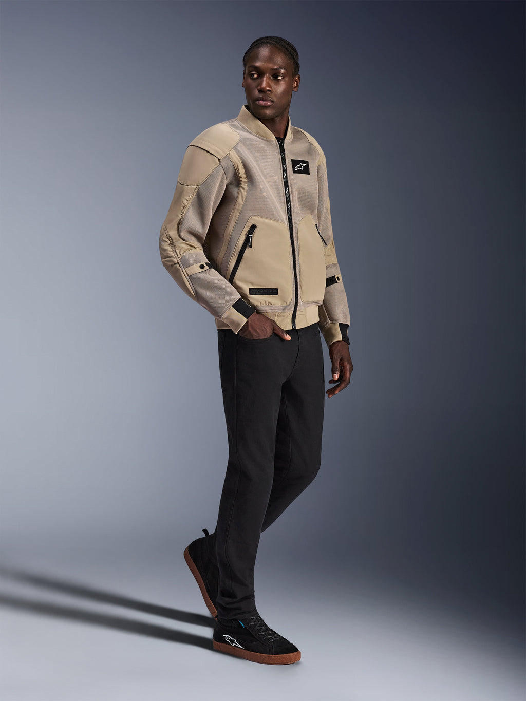Veste Flight Air Alpinestars, veste de moto urbaine, couleur Aluminum, portée par un mannequin avec un pantalon noir et des baskets noires, dotée de panneaux de ventilation en maille 3D et d'un design de style bomber, style urbain moderne pour la conduite citadine.