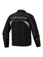 Veste Alpinestars Unite, vue arrière, noire avec panneaux réfléchissants gris foncé, logo Alpinestars à contour blanc dans le dos, veste de moto urbaine en softshell au design minimaliste