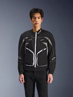 Veste Alpinestars Unite, veste de moto urbaine minimaliste, noir et gris foncé avec des accents blancs, dotée d'une fermeture éclair frontale blanche, de liserés réfléchissants et du logo Alpinestars sur la poitrine et les manches, style streetwear contemporain pour les motards.