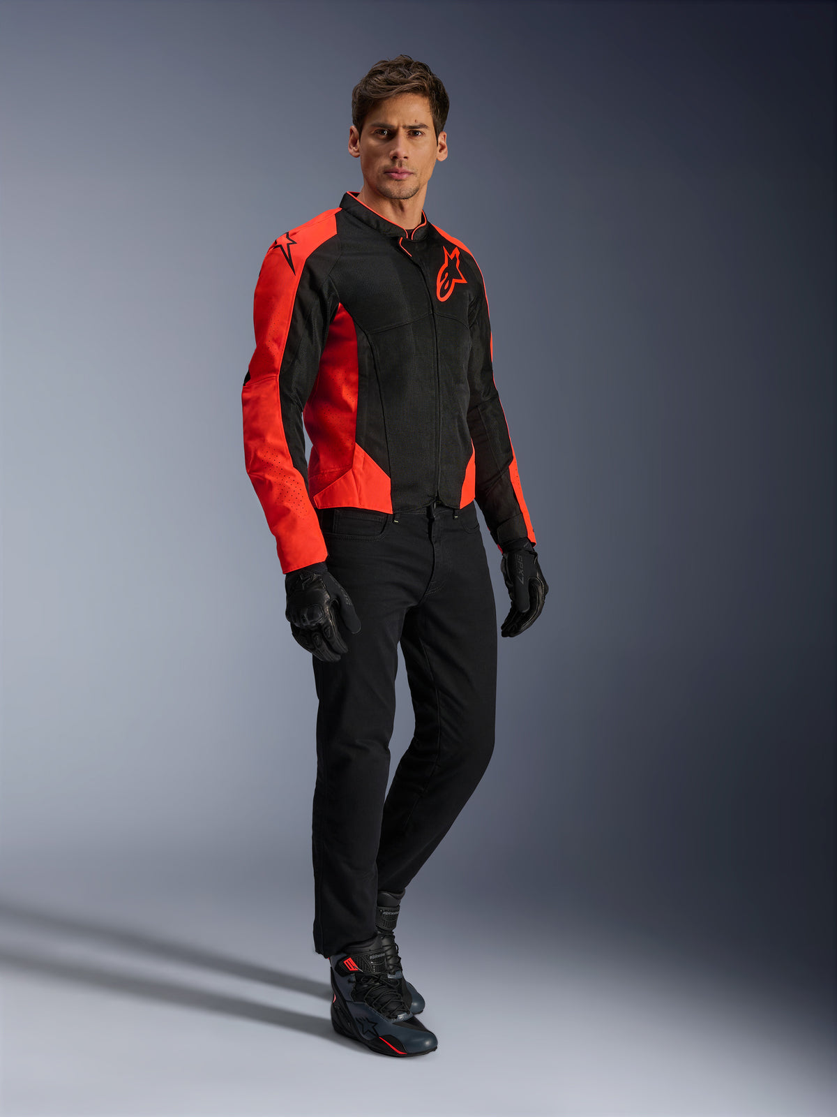 Veste Alpinestars Viper Air V4, veste de moto, rouge fluo et noir, portée par un mannequin avec un jean de moto noir, des gants noirs et des chaussures de moto, design en maille textile avec panneaux rouges vifs et logo étoilé, équipement de route sportif