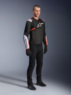 Veste Alpinestars T-Sps Air V2, Noir Blanc Rouge Fluo, portée par un mannequin homme avec un pantalon de moto noir et des gants, veste de moto en textile dotée de grands panneaux en mesh, de sections blanches aux épaules et aux avant-bras, et d'un logo Alpinestars distinctif sur la poitrine.