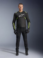 Veste Alpinestars T-Sps Air V2, noir et jaune fluo, veste de moto en textile avec panneaux en mesh, portée par un mannequin homme avec pantalon et gants noirs, arborant le logo Alpinestars blanc sur la poitrine, équipement de conduite sport urbain