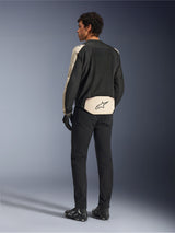 Veste Alpinestars T-SPS Air V2, veste de moto en textile, Noir Mastic Aluminium, vue de dos portée par un modèle, dotée de larges panneaux en maille technique pour la circulation de l'air, accents beige clair sur les manches et le bas du dos avec le logo Alpinestars, associée à un pantalon et des bottes noirs.