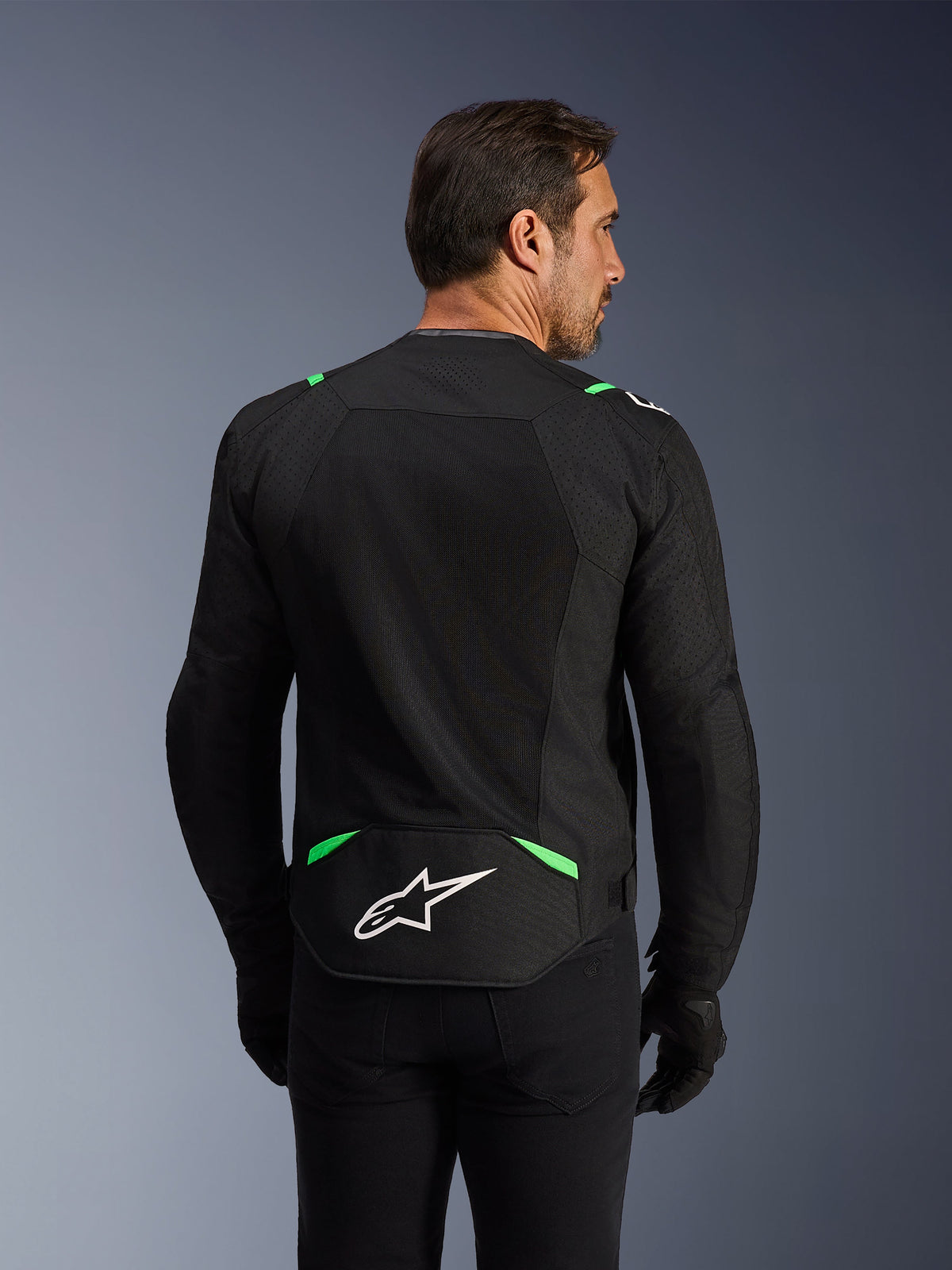 Veste Alpinestars T-SPS Air V2, veste de moto en textile, noir et vert fluo, vue arrière présentant de larges panneaux en maille technique pour la ventilation, logo Alpinestars blanc sur le bas du dos, coupe sport ergonomique pour la conduite urbaine