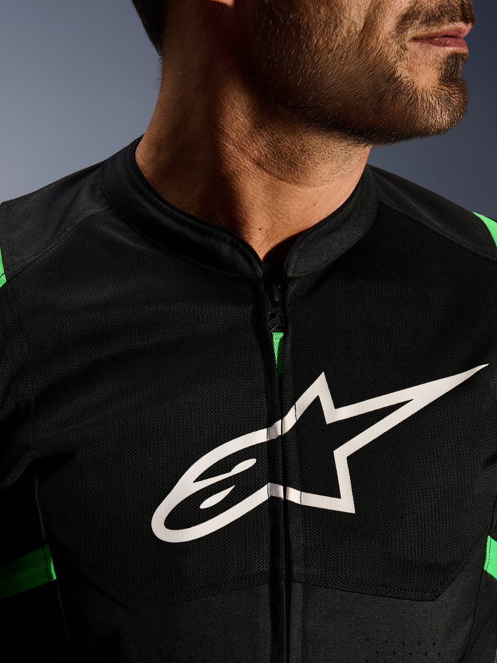 Gros plan de la veste Alpinestars T-SPS Air V2, noir et vert fluo, avec panneaux en maille technique respirante, fermeture éclair centrale et logo étoile Alpinestars blanc sur la poitrine, équipement moto haute performance