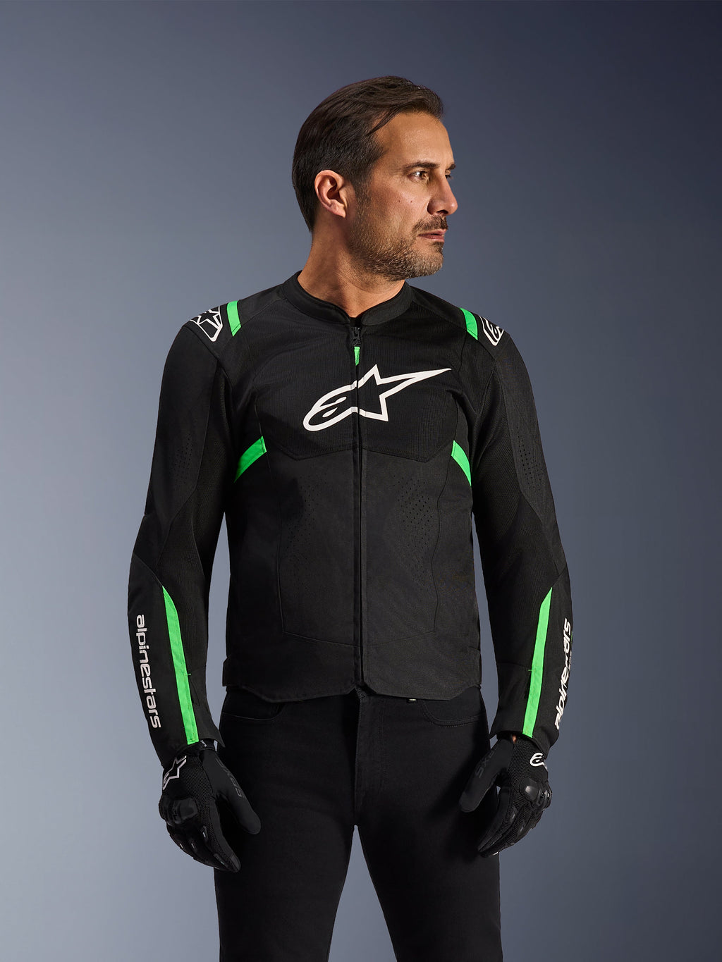 Veste Alpinestars T-SPS Air V2, veste de moto, noir et vert fluo, portée par un mannequin avec gants et pantalon de moto noirs, logo Alpinestars blanc sur la poitrine et accents vert fluo sur les épaules et les manches, panneaux en maille technique pour la ventilation, coupe sport pour la conduite urbaine