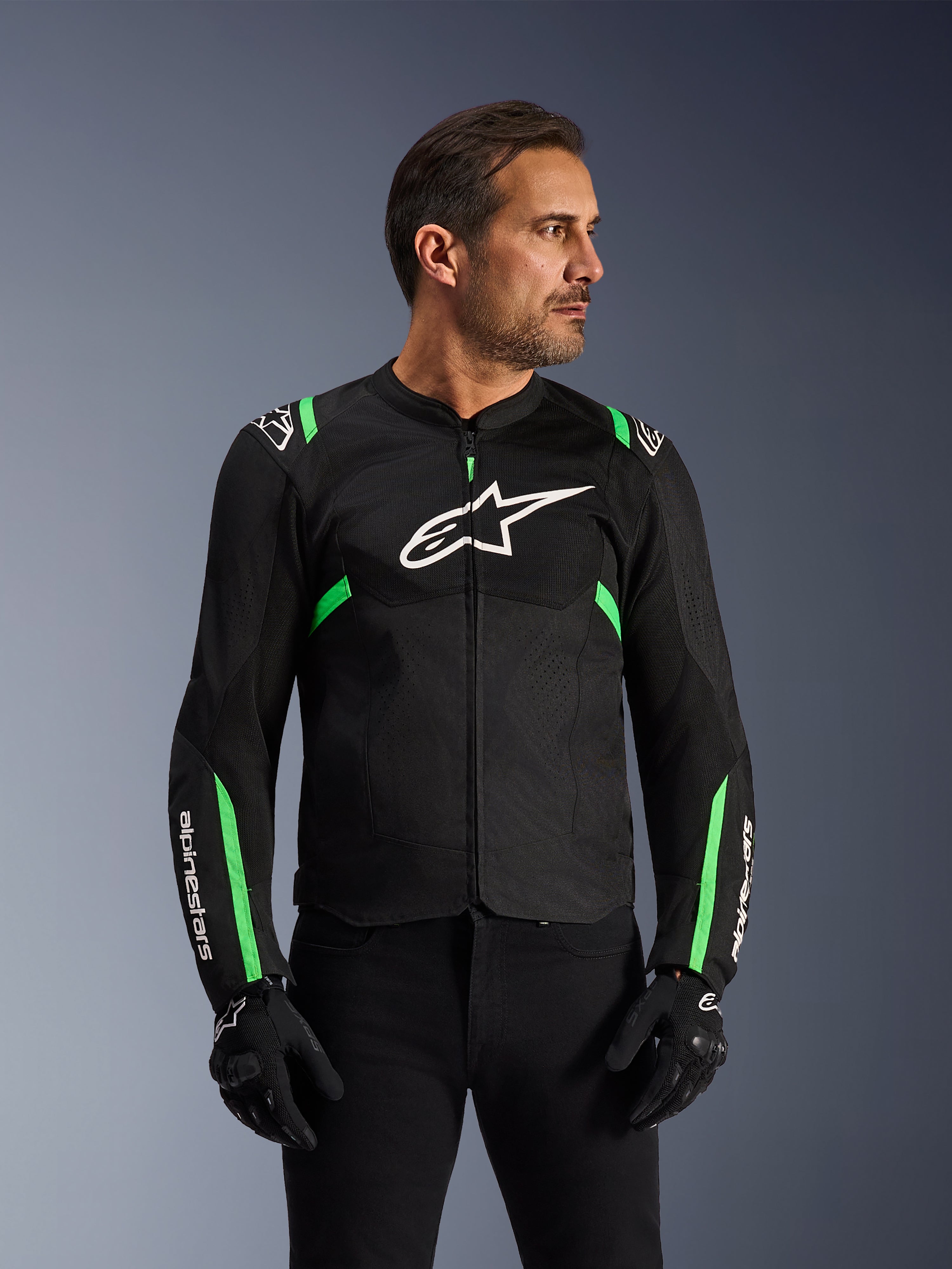 Veste Alpinestars T-SPS Air V2, veste de moto, noir et vert fluo, portée par un mannequin avec gants et pantalon de moto noirs, logo Alpinestars blanc sur la poitrine et accents vert fluo sur les épaules et les manches, panneaux en maille technique pour la ventilation, coupe sport pour la conduite urbaine