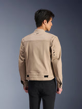 Veste Alpinestars Bruiser, veste de moto urbaine marron, vue arrière montrant les épaules plissées articulées et les sangles de réglage à la taille, portée avec un pantalon noir, équipement de moto contemporain inspiré du style workwear