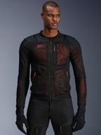 Veste Alpinestars Troop-Air Pro, veste de moto technique en mesh blindée en Noir et Rouge Fluo, portée par un mannequin, dotée de larges panneaux de ventilation en maille, d'une sous-couche rouge et de tirettes rouges, style de conduite urbain.