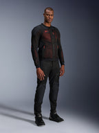 Veste Alpinestars Troop-Air Pro en Noir Rouge Fluo, veste de moto technique en mesh blindée portée par un mannequin homme avec un pantalon blindé noir assorti et des bottes montantes, portrait de studio en pied.