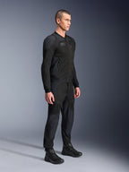 Veste Alpinestars Troop-Air Pro, veste technique ventilée et blindée, noire, portée par un mannequin avec un pantalon de moto et des bottes noirs assortis, dotée d'une structure technique en maille 2D avancée et de panneaux de ventilation respirants, équipement de conduite urbain contemporain.