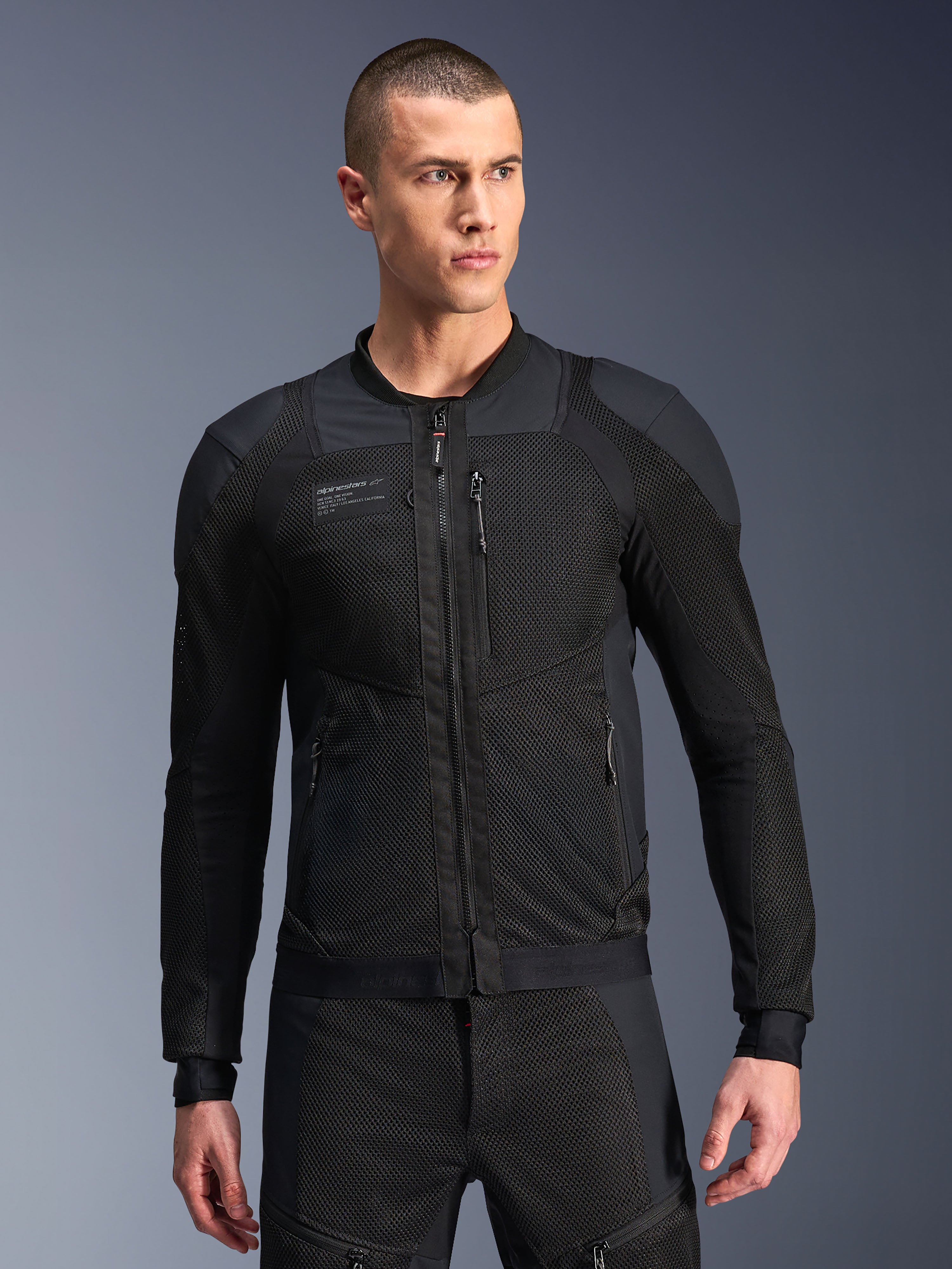 Veste Alpinestars Troop-Air Pro, veste de moto en mesh noire, modèle masculin portant une veste ventilée blindée avec structure en mesh technique 2D, fermeture éclair frontale, poches zippées, équipement de conduite technique haute performance