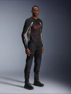 Veste Alpinestars Troop-Air, veste de moto en maille technique noir, gris cendré et rouge vif, portée par un mannequin avec pantalon et bottes noirs assortis, arborant un logo Alpinestars rouge sur la poitrine, équipement de conduite urbain contemporain