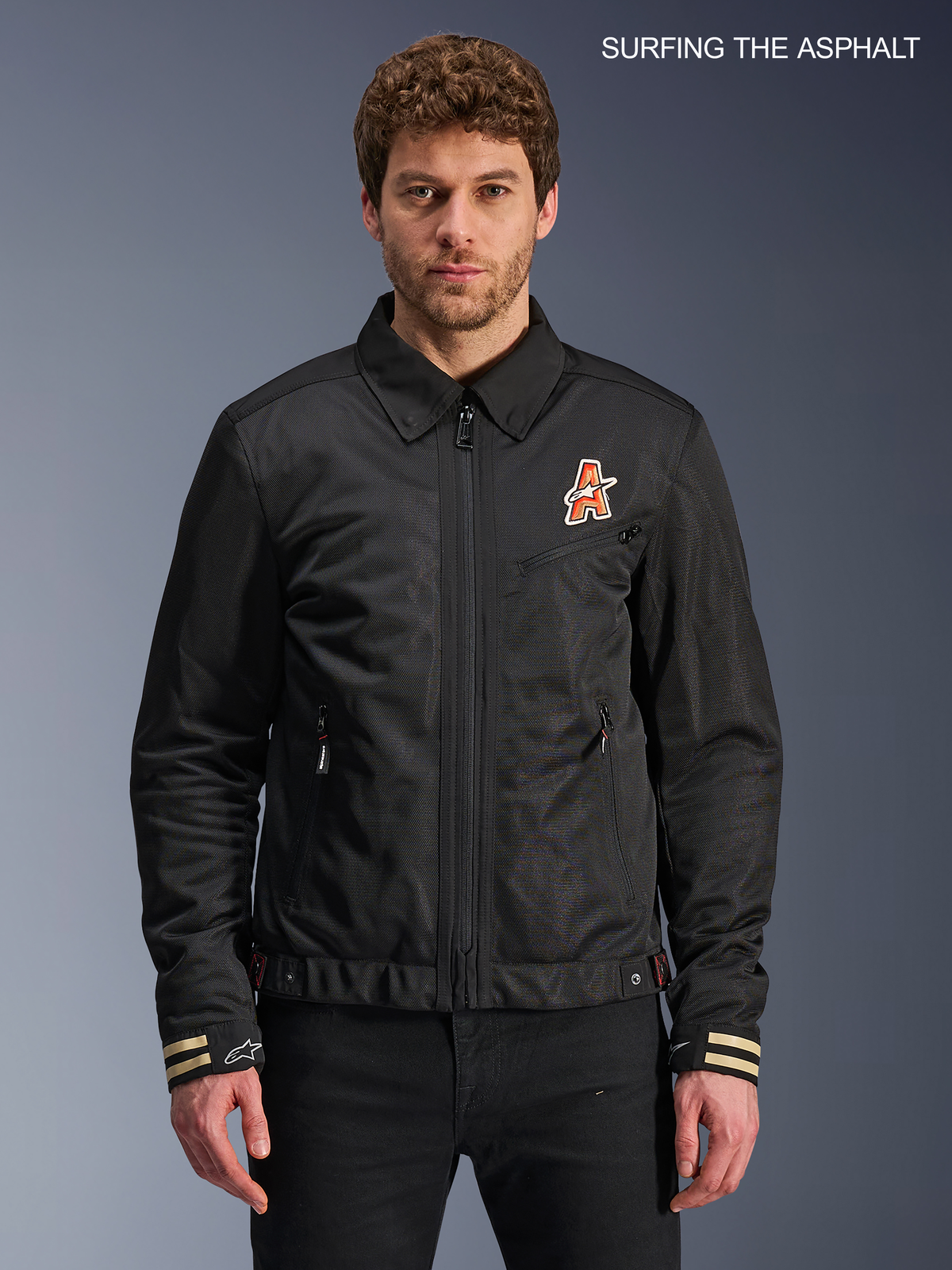 Alpinestars Ignite Air Jacket, men's urban motorcycle textile jacket in black, front view worn by a model featuring a traditional shirt collar, club-inspired chest graphics, and CE certified construction.