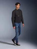 Veste Alpinestars Provoke, veste de moto urbaine, noire, portée par un mannequin homme avec un jean bleu et des baskets noires, design en textile technique avec petit logo Alpinestars, photo lifestyle en pied pour la conduite urbaine contemporaine