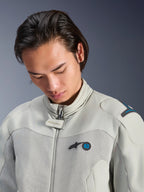 Modèle masculin portant la veste Alpinestars Circal-1 Air en gris métal avec des accents bleu méthyle, vue rapprochée mettant en avant le col, les panneaux de poitrine en maille et le logo minimaliste, équipement de moto urbain durable.